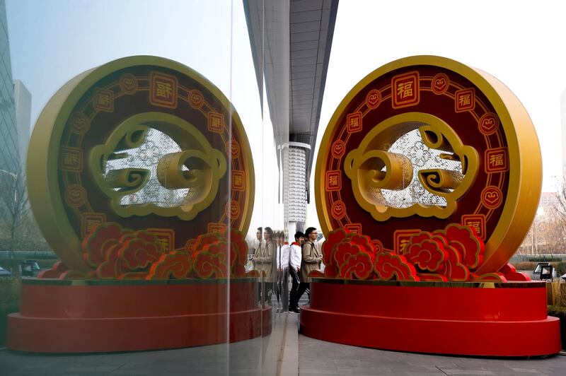 People walk by a golden prosperous pig structure on display outside a high-end commercial building at the Central Business District in Beijing, Wednesday, Feb. 27, 2019. A rich list by wealth compiler Hurun Report shows the market meltdowns in 2018 obliterated $1 trillion in wealth, with more than 212 of China's richest individuals losing their dollar billionaire status. (AP Photo/Andy Wong)