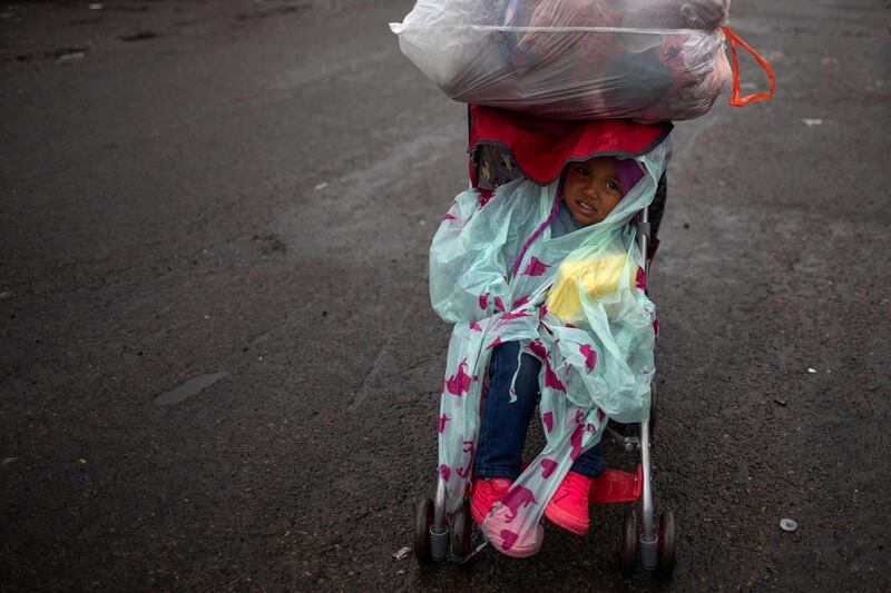 A migrant child departs a shelter during rainfall. Reuters