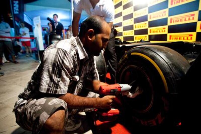 A man tries his hand at changing a F1 tyre in the Pirelli booth at Abu Dhabi Corniche during Abu Dhabi Grand Prix weekend.