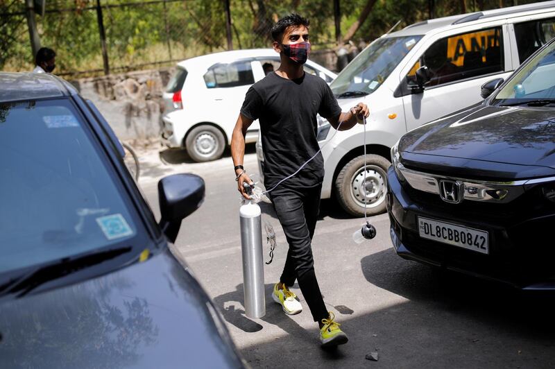 A man carries an empty oxygen cylinder to get it refilled at a private refilling station, for his relative who is suffering from the coronavirus disease, in New Delhi. Reuters