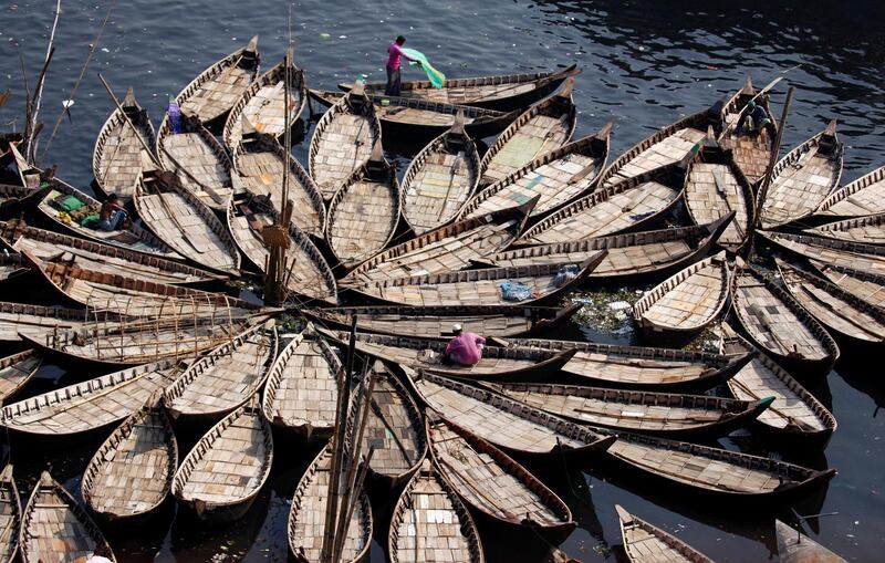 Bangladeshis sit on boats anchored in the Buriganga River in Dhaka. Monirul Alam / EPA