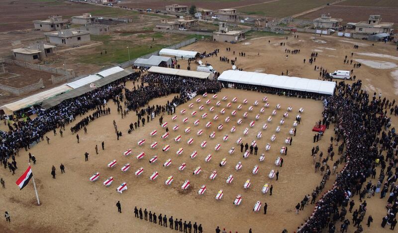 An aerial picture shows mourners gathering around coffins wrapped with the Iraqi flag during a mass funeral for Yazidi victims of ISIS in the northern Iraqi village of Kocho. AFP