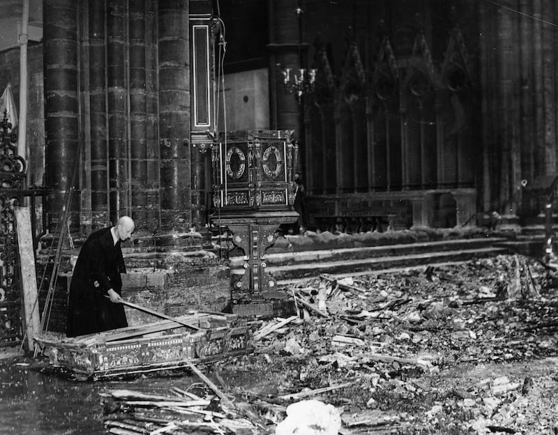 The verger of Westminster Abbey examines the wreckage of the magnificent canopy, lying broken in a pool of water during the Second World War in 1941