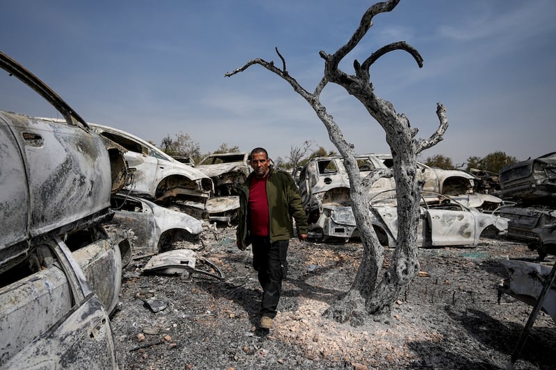 A Palestinian man walks past burnt cars in a scrapyard in Hawara. AP