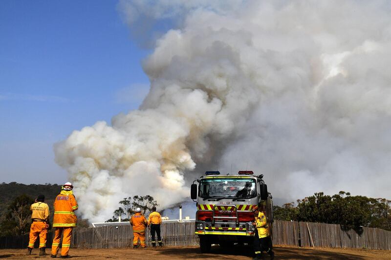Firefighters work as smoke rises from a bushfire in Penrose, in Australia's New South Wales state.  High temperatures and strong winds were expected to fan massive bushfires blazing across southeastern Australia on January 10, as authorities issued new emergency warnings after several days of cooler conditions brought some reprieve to affected communities. AFP