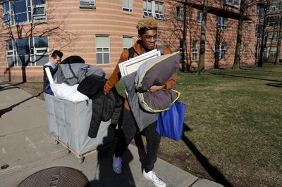 Northeastern University sophomore Philip Thomas, of Hamden, Conn., front, pulls a cart of belongings as he moves out of his residence hall as classmate Jarrett Anderson, of Las Vegas, left, assists him, Sunday, March 15, 2020, in Boston. Students have been asked by the school to move out of residence halls out of concern about the spread of the coronavirus. For most people, the new coronavirus causes only mild or moderate symptoms, such as fever and cough. For some, especially older adults and people with existing health problems, it can cause more severe illness, including pneumonia. The vast majority of people recover from the new virus. (AP Photo/Steven Senne)