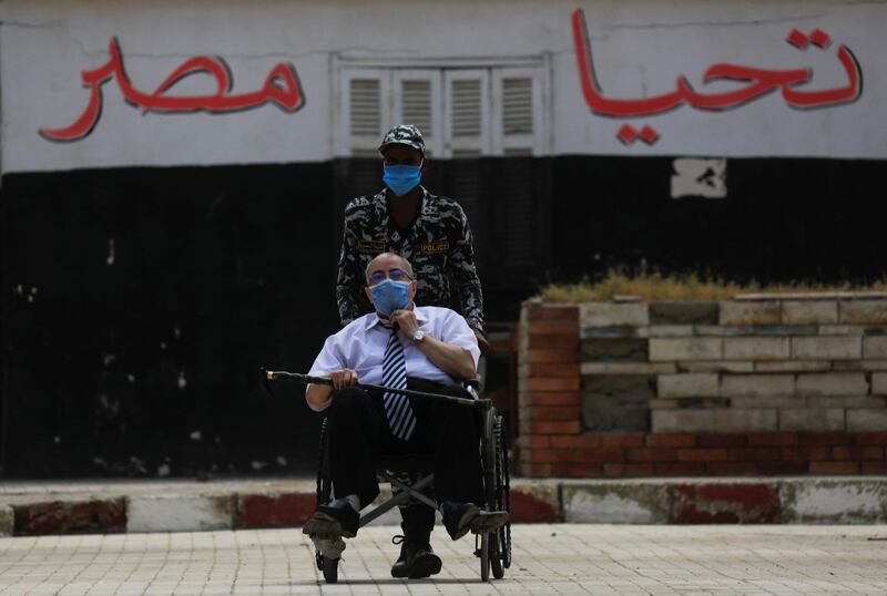 A security force member pushes a man in a wheelchair in front of a building where it's written "Long live to Egypt", during Egypt's senate elections in Cairo, Egypt. Reuters