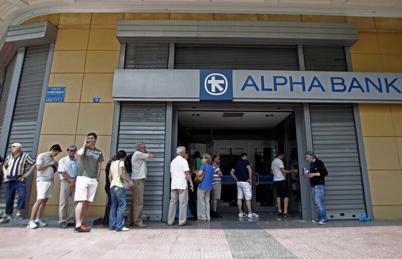 People wait in a queue to withdraw money from an ATM outside a branch of Greece’s Alpha Bank in Athens. Alexandros Vlachos / EPA