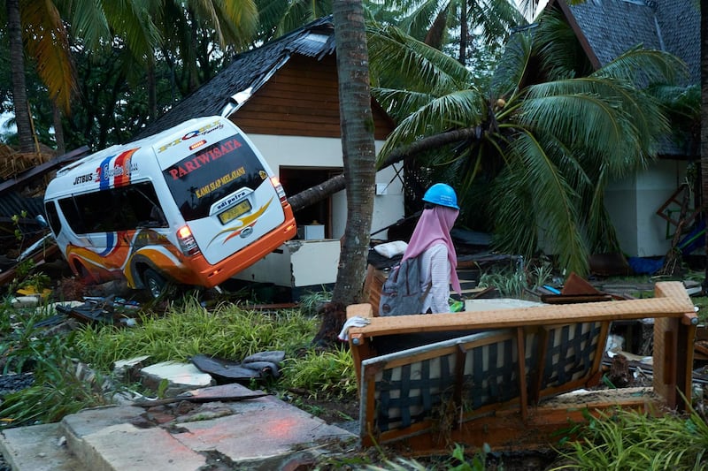 A rescue worker walks past a wrecked bus and bungalow at a resort hotel in Tanjung Lesung. Getty