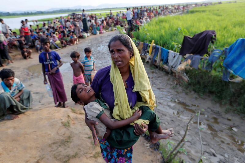 A Rohingya woman carries her daughter and searches for help as they wait to receive permission to continue their way to the refugee camps, in Palang Khali, Bangladesh. Jorge Silva / Reuters