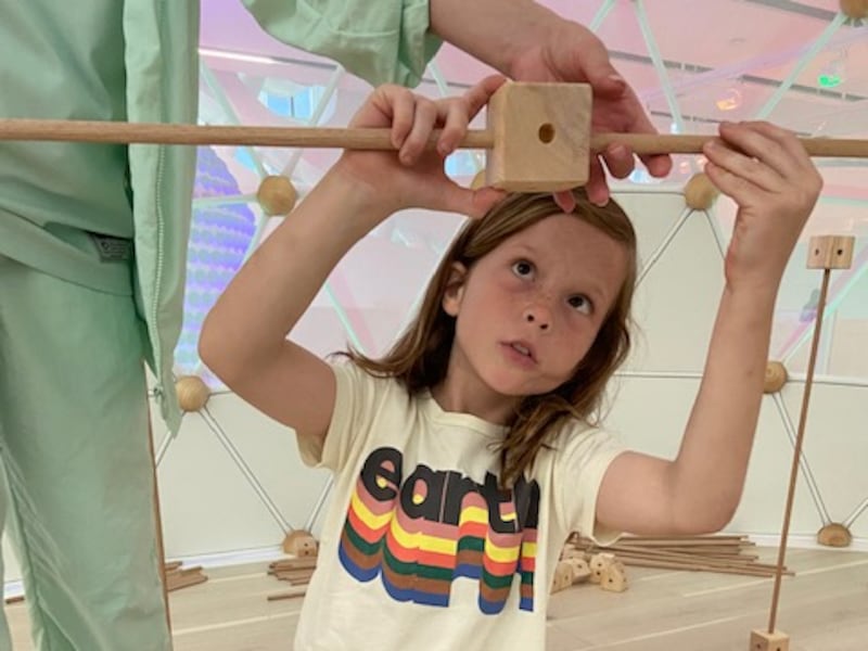 Indiana, 9, gets creative in the Build Lab, where an array of poles and brackets encourage creativity and design, and children are rewarded with a 'rain' shower.