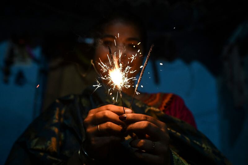 A woman lights sparklers as she celebrates Diwali, also known as the Festival of Lights. AFP