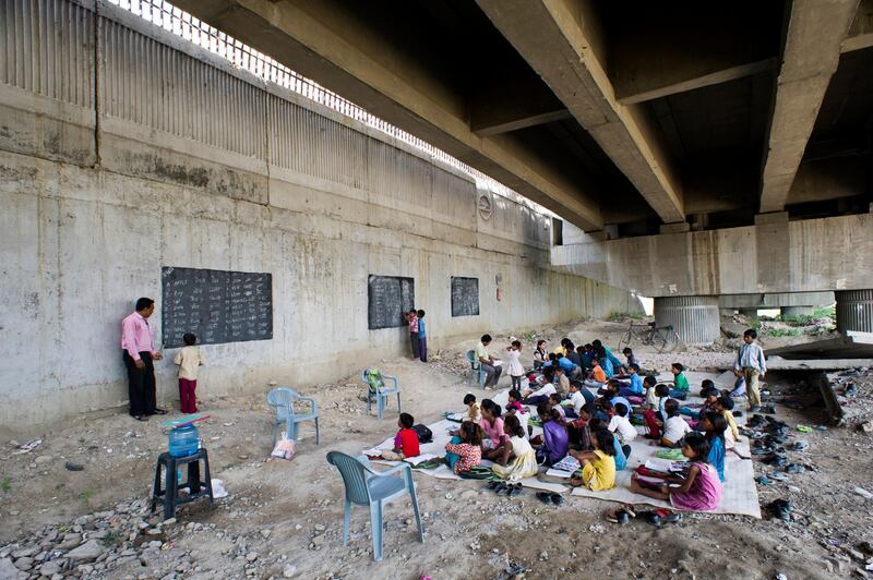 8th April 2013, Shakarpur, New Delhi, India. Rajesh Kumar Sharma (40) teaches children at the makeshift school he founded under a metro bridge near the Yamuna Bank Metro station in Shakarpur, New Delhi, India on the 8th April 2013. 

Rajesh Kumar Sharma (40), started this makeshift school a year ago. Five days a week, he takes out two hours to teach when his younger brother replaces him at his general store in Shakarpur. His students are children of labourers, rickshaw-pullers and farm workers. This is the 3rd site he has used to teach under privileged children in the city, he began in 1997 fifteen years ago. 

PHOTOGRAPH BY AND COPYRIGHT OF SIMON DE TREY-WHITE

+ 91 98103 99809
+ 91 11 435 06980
+44 07966 405896
+44 1963 220 745
email: simon@simondetreywhite.com