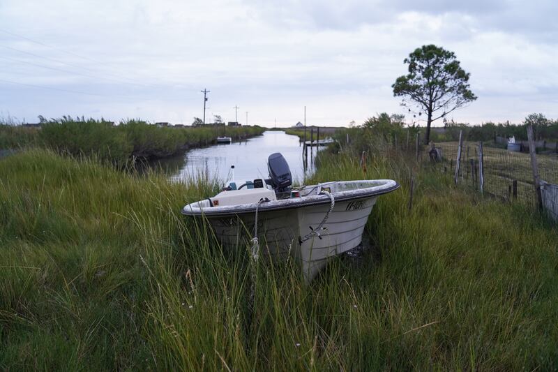 A boat sits on land next to a marshy canal. Boats are everywhere on Tangier.