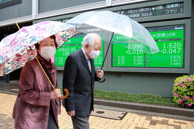 A couple pass an electronic stock board of a securities company in Tokyo. Asian stock markets rose on Wednesday after Wall Street hit a high following an uptick in US inflation and an order by regulators to suspend use of Johnson & Johnson's coronavirus vaccine. AP Photo