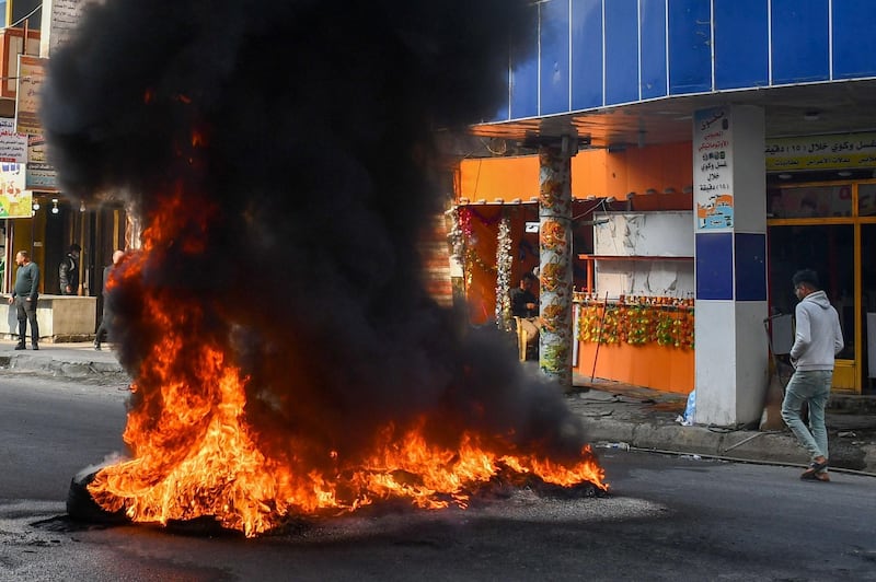 An Iraqi man walks next to burning tyres during clashes with police during anti-government demonstrations in the city of Nasiriyah in the Dhi Qar province in southern Iraq.  AFP