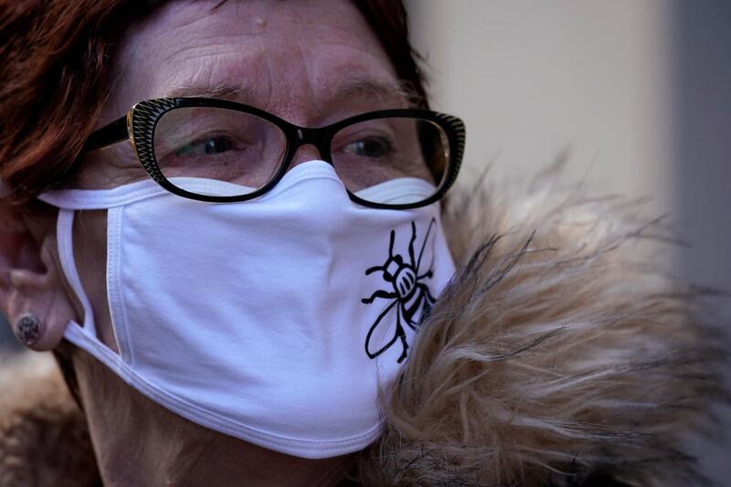 A woman wearing a face mask with the Manchester Worker Bee logo walks through the city centre in Manchester. The English city was placed in the second of three alert levels this week when the British government introduced a new system for assessing Covid-19 risk. Getty Images