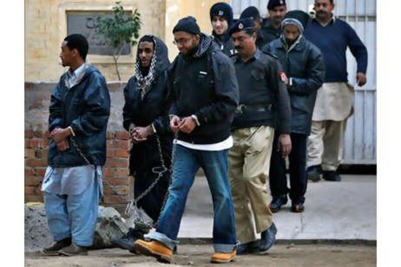 A Pakistani policeman escorts hand-cuffed men identified as Aman Hassan Yemer, left, Ahmed Abdulah Minni, second left, Waqar Hussain Khan, right, Ramy Zamzam, back left, and Umar Farooq, back right, as they leave a police station after their court appearance in Sargodha, Punjab province, on January 4, 2010.