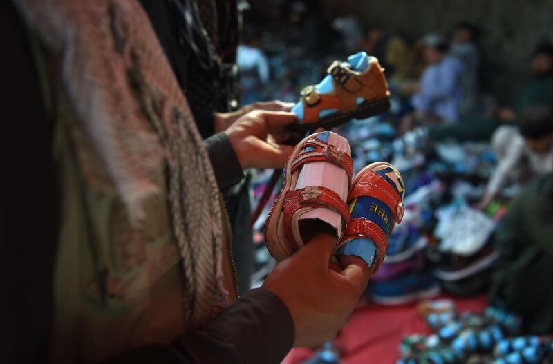 An Afghan man looks at sandals for children ahead of Eid Al Fitr, at a roadside in Kabul. AFP