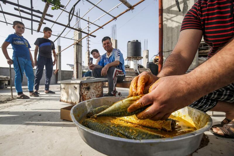 Palestinian family members prepare to smoke mackerel on the roof of their house in preparation for the upcoming Eid al-Fitr holiday which marks the end of the Islamic holy month of Ramadan, in the southern Gaza Strip city of Rafah.   AFP