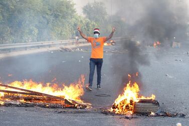 A demonstrator gestures near burning objects on the road during a curfew, two days after nationwide anti-government protests turned violent, in Baghdad, Iraq October 3, 2019. REUTERS/Khalid al-Mousily