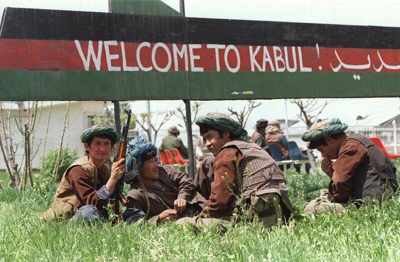 Afghan Uzbek militiamen belonging to safe-styled General Abdul Rashid Dostam, an Uzbek warlord, relax on a patch grass beneath a sign reading "Welcome to Kabul" 01 May 1992 at the VIP section of the airport in the Afghan capital. Words on the sign are drawn across the colours of the Afghan national flag flown under the late Soviet-backed communist regime. Dostam, in 1992 mutinied against to government of Mohammed Najibullah allying with Ahmed Shah Massoud. Together, they captured Kabul. AFP PHOTO DOUGLAS E. CURRAN (Photo by DOUGLAS E. CURRAN / AFP)