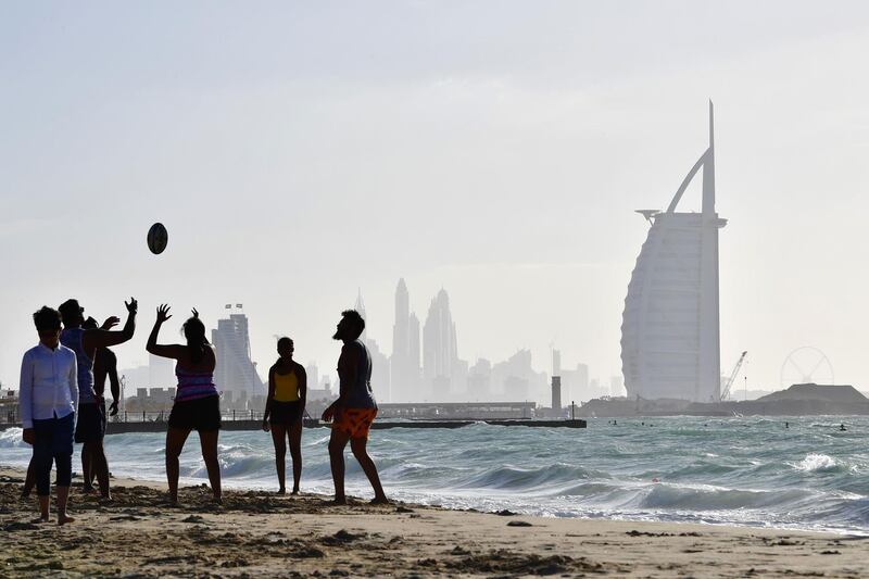 A picture taken on January 11, 2019, shows people playing ball in front of Burj Al Arab hotel in the UAE Emirate of Dubai. / AFP / GIUSEPPE CACACE
