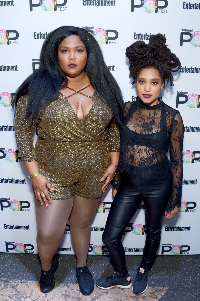 Lizzo, left, in a gold, shimmering romper, and Sophia Eris pose backstage at Entertainment Weekly's PopFest on October 29, 2016. Getty Images