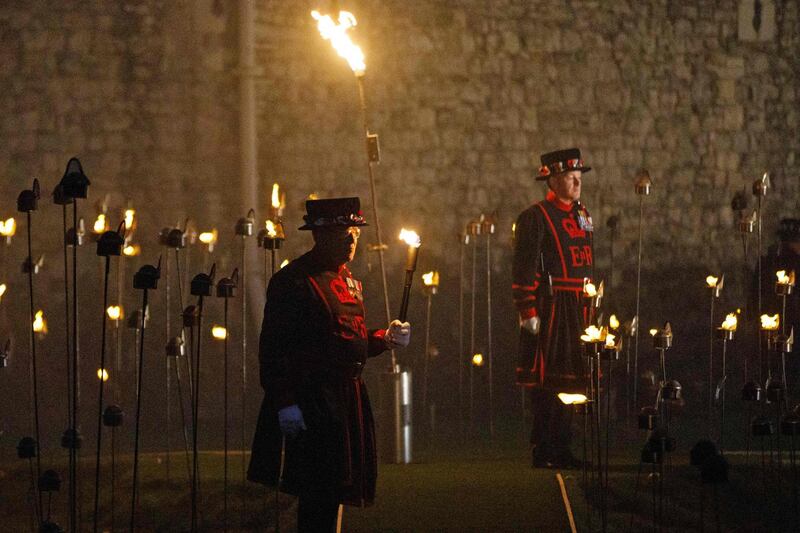Yeoman Warders, commonly known as a 'Beefeaters' stand by after lighting the first of thousands of flames in a lighting ceremony in the dry moat of the Tower of London, as part of an installation called 'Beyond the Deepening Shadow: The Tower Remembers', marking the centenary of the end of the First World War. AFP