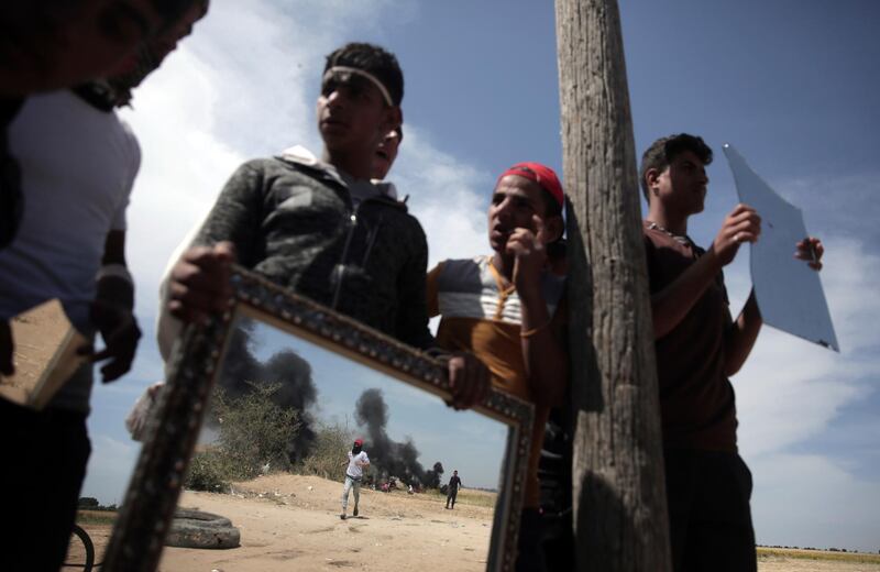 Palestinian protestors are seen through mirrors used to reflect the sun light at Israeli soldiers during a protest next to the Gaza Strip border with Israel, east of Khan Younis, Monday, April 2, 2018. (AP Photo/ Khalil Hamra)