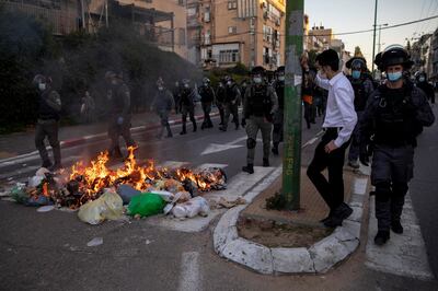 Israeli police officers march by burning garbage during clashes with ultra-Orthodox Jews in Bnei Brak, Israel, Sunday, Jan. 24, 2021. Ultra-Orthodox demonstrators clashed with Israeli police officers dispatched to close schools in Jerusalem and Ashdod that had opened in violation of coronavirus lockdown rules, on Sunday. (AP Photo/Oded Balilty)