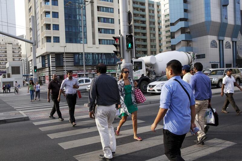 People walk across the intersection of Sheikh Zayed Bin Sultan and Hamdan Bin Mohammed streets in Abu Dhabi. Christopher Pike / The National