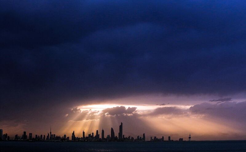 The setting Sun breaks through cloud over Kuwait City. AFP