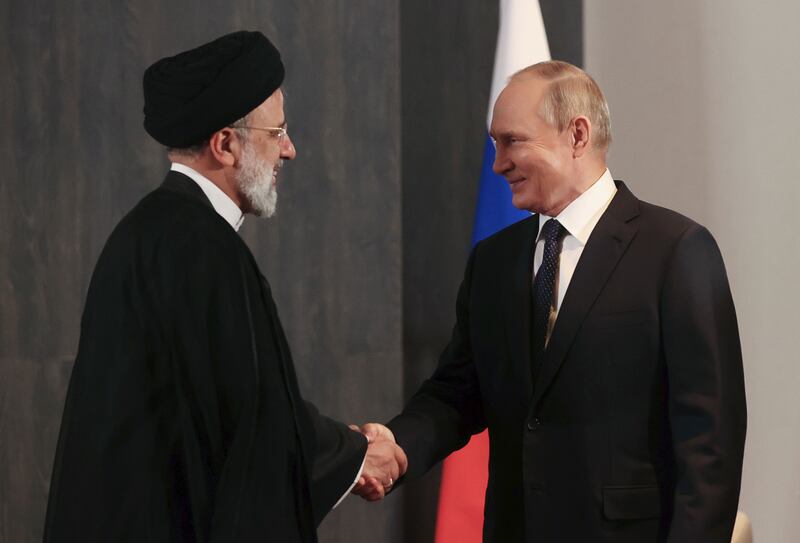 Mr Putin, right, and Iranian President Ebrahim Raisi shake hands during their meeting. AP