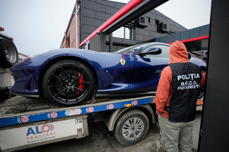 A police officer looks on as a luxury vehicle is seized on the outskirts of Bucharest, in the case against Tate. AP