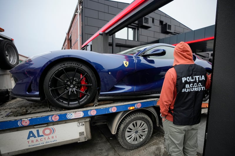 A police officer looks on as a luxury vehicle is seized on the outskirts of Bucharest, in the case against Tate. AP