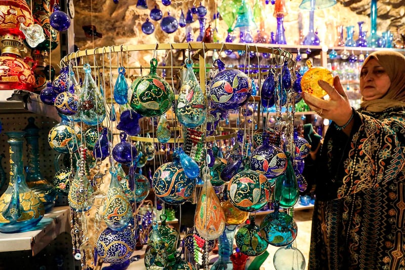 A woman hangs glass Christmas tree ornaments on display at a glass-blowing workshop in the old city of the Palestinian city of Hebron in the occupied West Bank on December 8, 2020. AFP
