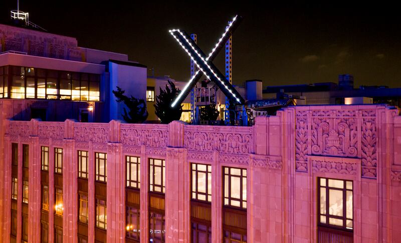 Workers install lighting on an 'X' sign on top of the company headquarters in San Francisco, on Friday. AP