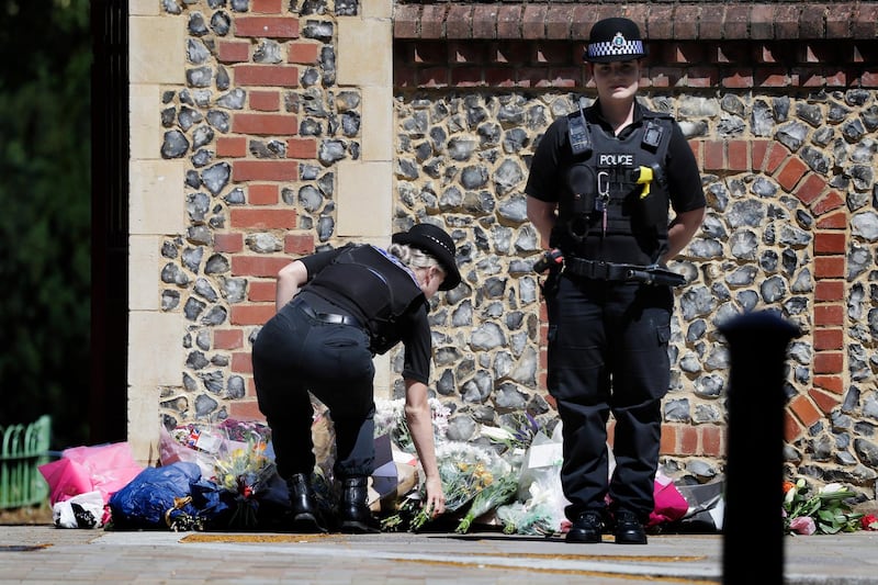 A Police officer places flowers from a woman at the scene of a fatal multiple stabbing attack in Forbury Gardens, central Reading, England, Monday June 22, 2020. AP Photo
