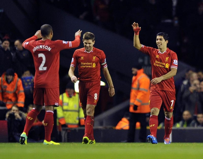 Liverpool's Luis Suarez, right, celebrates after scoring the second goal of the game with teammates Steven Gerrard, center, and Glen Johnson during their English Premier League soccer match against Norwich City at Anfield in Liverpool, England, Wednesday Dec. 4, 2013. AP Photo/Clint Hughes