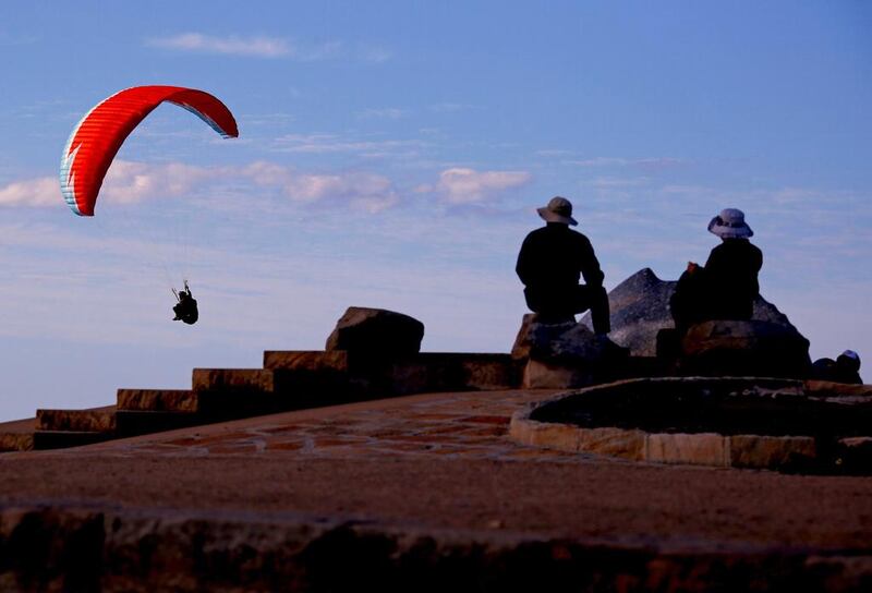 People watch as a paraglider flies past them as they sit atop Long Reef Point on the first day of Spring in Sydney, Australia. David Gray / Reuters