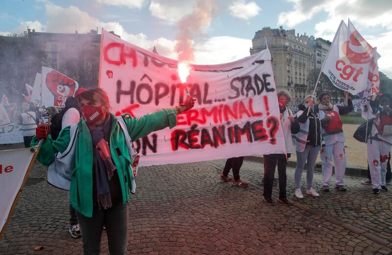 A medical worker fires a red flare in Paris. French President Emmanuel Macron has announced that millions of French citizens in several regions around the country, including in Paris, will have to respect a 9pm curfew from this Saturday. AP Photo