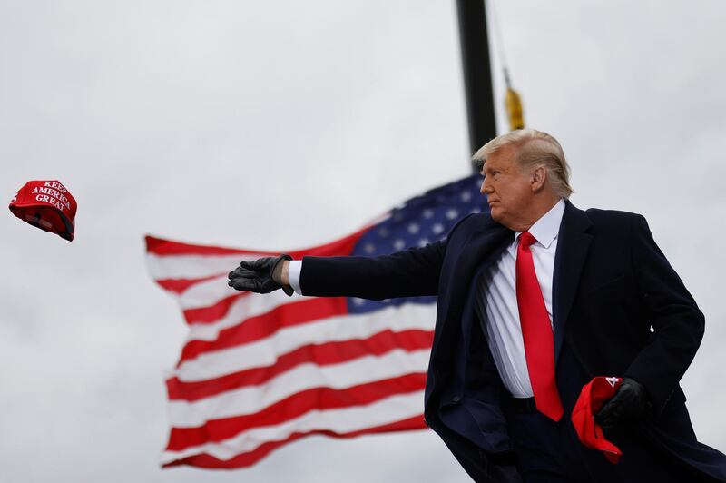 U.S. President Donald Trump tosses out "Make America Great Again" (MAGA) caps as he arrives for a campaign rally at Oakland County International Airport in Waterford Township, Michigan, U.S., October 30, 2020. REUTERS/Carlos Barria