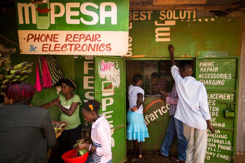Residents transfer money using the M-Pesa banking service at a store in Nairobi, Kenya, on Sunday, April 14, 2013. In the six years since Kenya's M-Pesa brought banking-by-phone to Africa, the service has grown from a novelty to a bona fide payment network. Photographer: Trevor Snapp/Bloomberg
