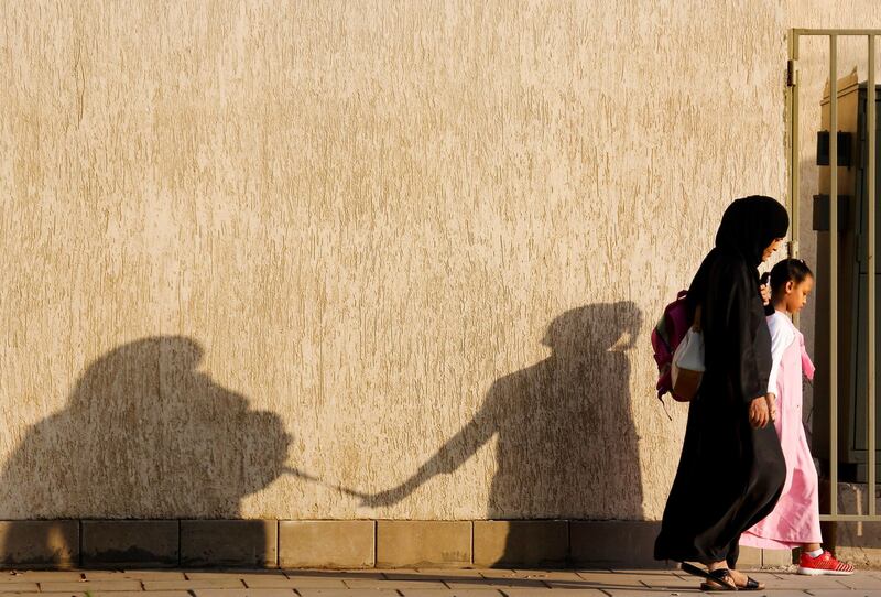 The shadow of the mother and her daughter is reflected on a wall as they walk to the school, in Jeddah, Saudi Arabia. AP Photo