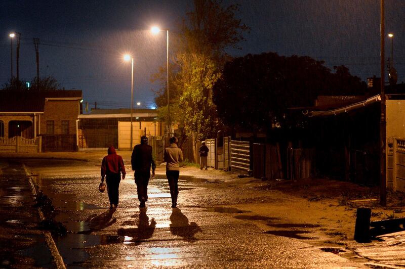 People walk down a street during a patrol of members of the Neighborhood Safety Team (NST) in Bonteheuwel, a crime-ridden suburb, on July 30, 2019, in Cape Town. The NST is made up of trained law-enforcement officers whose focus is on enforcement interventions including stop-and-search operations, visible patrols and vehicle checkpoints. South Africa in July deployed some 1,300 soldiers to shore up the police forces which has been battling deadly gang violence ravaging the area. A new report on urban safety released by the South African Cities Network this year, showed Cape Town recorded the highest murder rates in the country at 69 people killed per 100,000 -- double the national average of rate recorded last year.  / AFP / RODGER BOSCH
