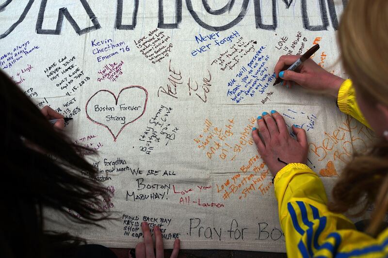 BOSTON, MA - APRIL 16: People write messages on a memorial canvas during a vigil for victims of the Boston Marathon bombings at Boston Commons on April 16, 2013 in Boston, Massachusetts. The twin bombings, which occurred near the marathon finish line, resulted in the deaths of three people while hospitalizing at least 140. The bombings at the 116-year-old Boston race, resulted in heightened security across the nation with cancellations of many professional sporting events as authorities search for a motive to the violence.   Spencer Platt/Getty Images/AFP== FOR NEWSPAPERS, INTERNET, TELCOS & TELEVISION USE ONLY ==
 *** Local Caption ***  925926-01-09.jpg