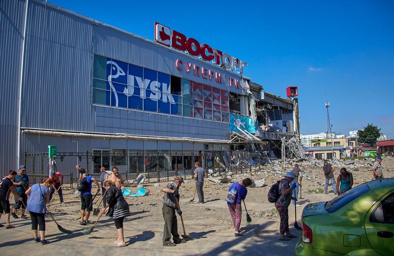Volunteers clear debris near a damaged shopping mall after night shelling in Kharkiv, Ukraine. EPA