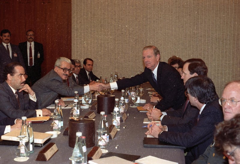 U.S. Secretary of State James Baker (5th R) and Iraqi Foreign Minister Tariq Aziz shake hands at the request of photographers at the start of their meeting in Geneva January 9, 1991.    REUTERS/Landov   QUALITY FROM SOURCE