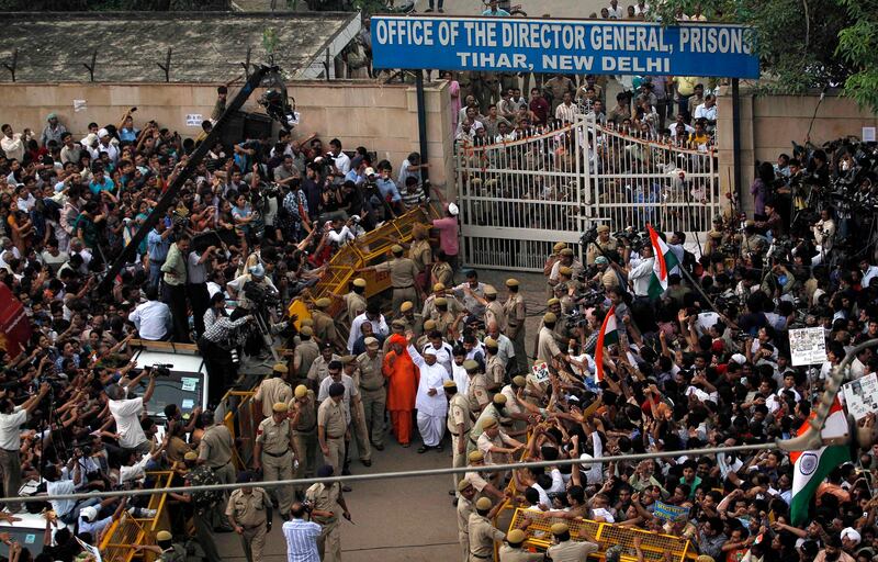 India's most prominent anti-corruption crusader Anna Hazare, center, waves to the crowd after emerging from the gates of Tihar prison where he was lodged since Aug. 16, in New Delhi, India, Friday, Aug. 19, 2011. Nearly 2,000 men, women and schoolchildren had gathered outside Tihar Jail on Friday morning to catch sight of the white-clad activist who has channeled the tactics of freedom fighter Mohandas K. Gandhi into his fight to force the government to adopt his proposals for an anti-corruption law. (AP Photo/Saurabh Das) *** Local Caption ***  India Corruption Protest.JPEG-05798.jpg